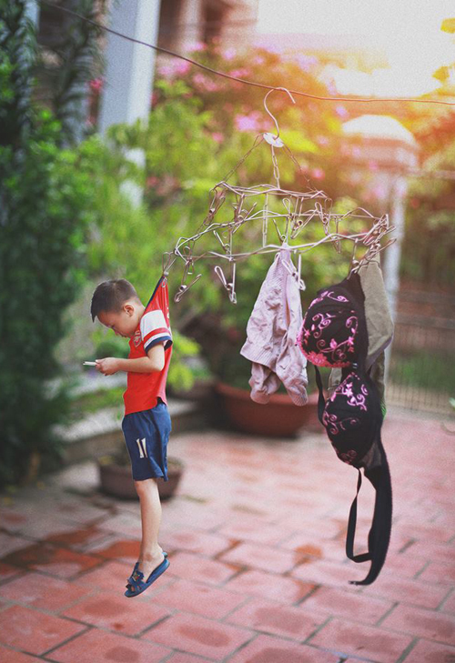 'Nhiều ông bố bà mẹ chọn cách đưa cho con đồ chơi công nghệ để nó im lặng, để nó không khóc và việc trông trẻ sẽ như phơi quần áo: Phơi ra lúc sáng đi làm rồi trưa về cất chúng...', tác giả bộ ảnh, chàng trai 23 tuổi, Đỗ Xuân Bút chụp và tự dẫn dắt về câu chuyện 'đứa trẻ công nghệ' của mình như vậy.